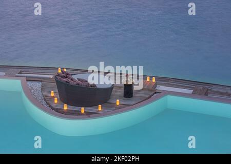 Kerzen am Pool am Abend. Romantisches privates Abendessen mit Liegestühlen und Meerblick. Luxuriöse Sommer-Flitterwochen, romantisches Reiseziel für Paare Stockfoto