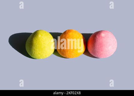 Bunte Gelee-Bonbons auf pastellblauem Grund. Minimalistischer Farbdruck. Sommerhintergrund. Süßes Sonnenlicht mit scharfen Schatten. Sonniger Schatten am Tag. Stockfoto