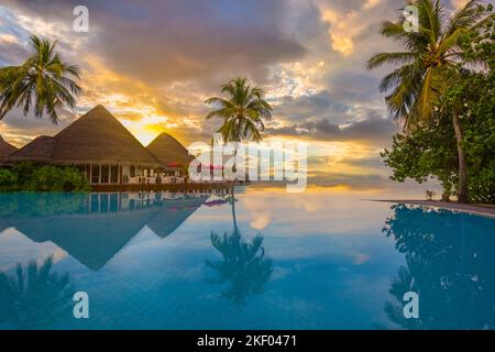 Wunderschöne Sonnenuntergangsszene am Strand. Blick auf den farbenfrohen Himmel und die Wolken mit ruhigem Meer und entspannter tropischer Stimmung über der Wasservilla. Exotische Reiselandschaft Stockfoto
