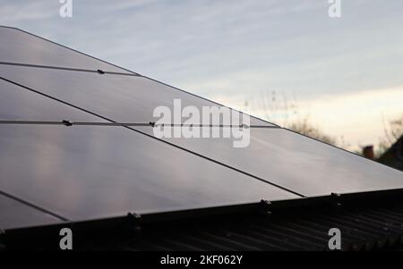 Ein Handwerker, der Sonnenkollektoren auf einem Haus installiert. Stockfoto