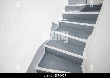 Leere Steintreppe in der Nähe der weißen Mauer, abstrakte Nahaufnahme auf Santorini Island, Griechenland. Weiße Architektur mit grauen Stufen. Minimale Gebäudeteile Stockfoto