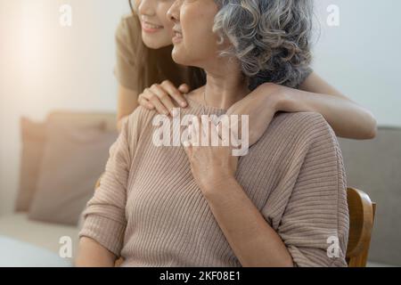 Liebevolle Erwachsene Tochter umarmt ältere Mutter auf der Couch zu Hause, Familie genießen zarten Moment zusammen, junge Frau und reife Mutter oder Großmutter suchen Stockfoto