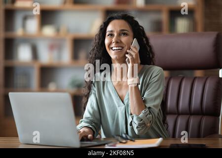 Freundliche, hübsche junge Geschäftsfrau aus dem Nahen Osten, die einen Anruf hatte Stockfoto
