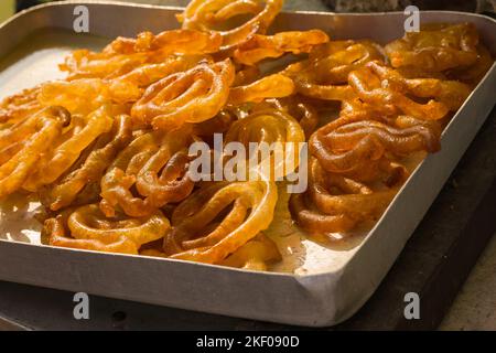 jalebi oder Jilipi werden auf einem Tablett aufbewahrt. Traditionelles indisches Dessert, das während der ratha yatra zubereitet wird. Stockfoto