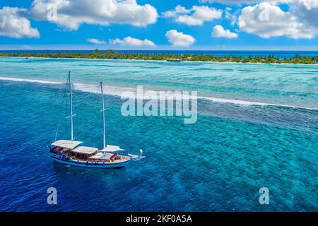 Kleine Yacht, die im tropischen Meer über das Korallenriff in der Lagune des Indischen Ozeans segelt. Exotische Insellandschaft, Luftaufnahme, ruhige Naturlandschaft Stockfoto