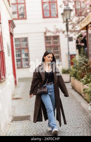 Junge und hübsche Frau in trendigen Herbst Kleidung zu Fuß entlang der schmalen Straße in prag, Stock Bild Stockfoto