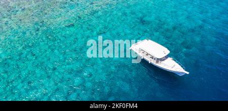 Kleine Luxusyacht vor Anker im flachen Wasser. Luftaufnahme der Ferienjacht am Strand der tropischen Insel auf dem blauen Riffmeer, Outdoor-Sport, Sommeraktivität Stockfoto