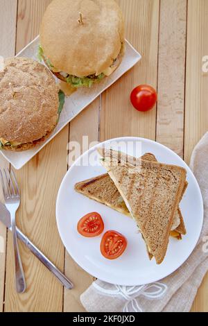 Vegane Küche – hausgemachte Burger und Sandwiches mit Stecklingen und Gemüse auf pflanzlicher Basis. Stockfoto