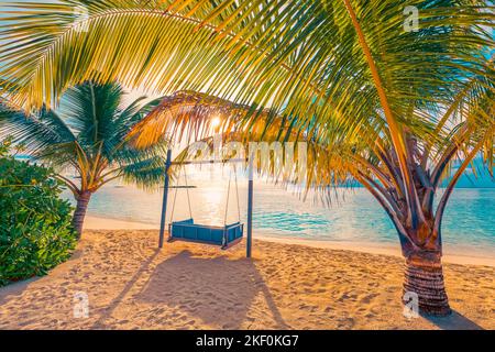 Tropischer Sonnenuntergang am Strand als Sommerpanorama mit Strandschaukel oder Hängematte und weißem Sand und ruhigem Strandbanner. Ruhiger Strand Stockfoto