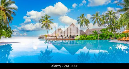 Touristenlandschaft am Strand. Luxuriöses Strandresort am Pool, Swimmingpool und Liegestühle Liegen, Sonnenschirme mit tropischen Palmen Stockfoto