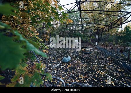 Verlassene Vergnügungsfahrt in der Geisterstadt Pripyat in der Sperrzone von Tschernobyl, Scooter in Herbstfarben Stockfoto