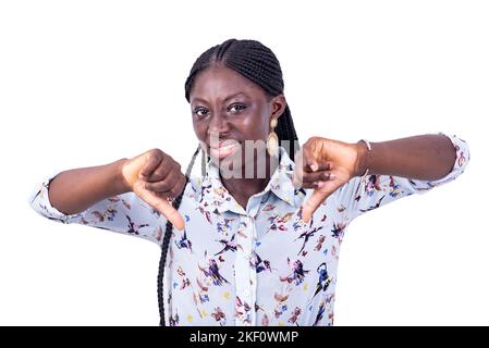 Porträt einer schönen unzufrieden jungen Frau, die Daumen nach unten zeigt, während sie auf die Kamera schaut. Stockfoto