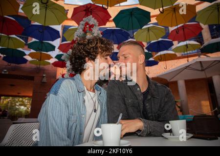 Ein homosexuelles Paar trinkt in der Weihnachtszeit während eines Moments der Zärtlichkeit Kaffee Stockfoto