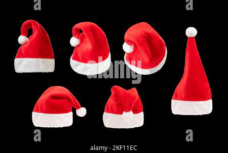 Rot-weißer weihnachtshut auf schwarzem Hintergrund. weihnachtsmann Mütze aus verschiedenen Winkeln auf dem schlichten dunklen Hintergrund. Stockfoto