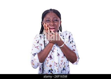 Eine junge Frau mit Zöpfen, die auf weißem Hintergrund stehen und Zahnschmerzen spüren. Stockfoto