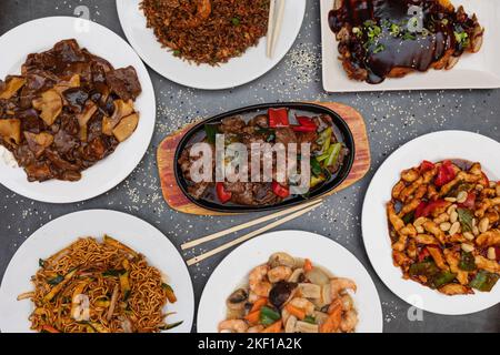 Verschiedene chinesische Gerichte. Chinesische Nudeln, gebratener Reis, Knödel, gebratene Ente, Yakisoba. Berühmte chinesische Gerichte auf dem Tisch. Draufsicht. Chinesische res Stockfoto