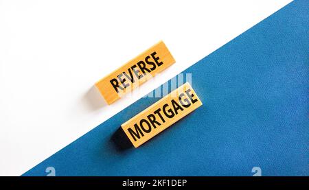 Umgekehrtes Hypothekensymbol. Konzept Wörter Reverse Mortgage auf Holzblöcke. Schöner weißer und blauer Hintergrund. Business- und Reverse-Mortgage-Konzept. Stockfoto