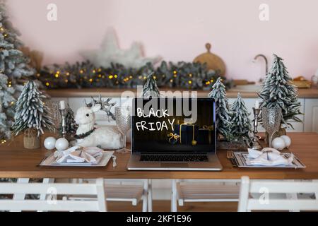 Black Friday Shopping-Konzept auf dem schwarzen Bildschirm des Laptops vor verschwommenem weihnachtslicht Hintergrund geschrieben Stockfoto
