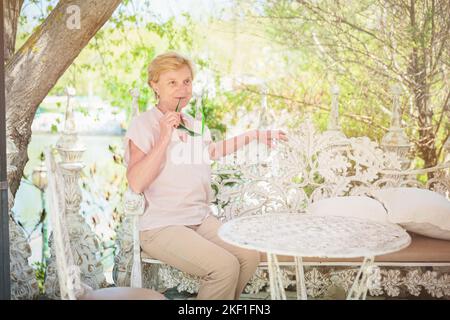 Reife Frau, die alleine auf der Terrasse des Cafés sitzt Stockfoto