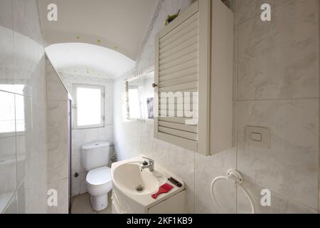 Badezimmer mit weißen Porzellanhähnen, Holzmöbeln und Toilette in einer Ecke Stockfoto