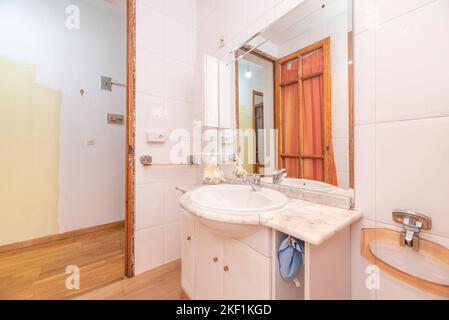 Toilette mit Spiegel an der Wand, weiße Holzmöbel mit Marmorplatte und Holzdetails an den Türen Stockfoto