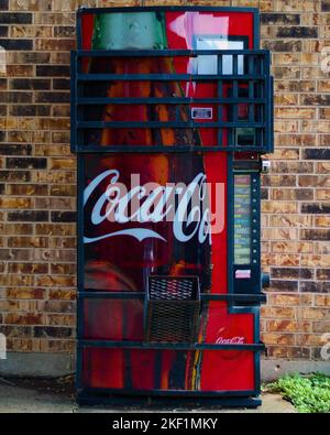 Eine vertikale Aufnahme einer alten Coca-Cola-Maschine mit Käfig. Stockfoto