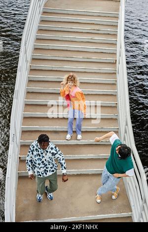 Grafische Draufsicht auf eine Gruppe von jungen Menschen, die auf einer Treppe im Freien tanzen und farbenfrohe Kleidung im Straßenstil tragen Stockfoto