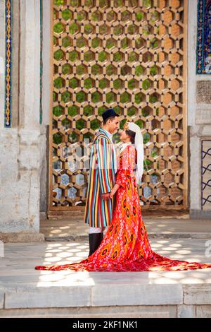 Samarkand, Usbekistan - 18. April 2021: Braut und Bräutigam in traditionellen usbekischen Kleidern in der antiken Stadt Registan, Samarkand in Usbekistan Stockfoto