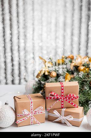 Dekorative Weihnachtsbäume und Geschenkboxen auf Holztisch gegen verwischtes Licht Stockfoto