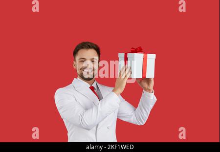 Lächelnder Mann im Anzug mit Geschenkbox Stockfoto