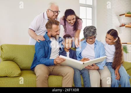 Freundliche Familie Eltern, Kinder, Großeltern suchen Familie Fotoalbum zusammen sitzen auf der Couch. Stockfoto