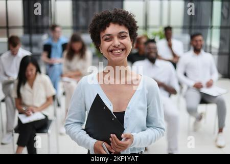Glückliche Geschäftsfrau im Gespräch mit ihren Kollegen auf Seminar im Büro. Stockfoto
