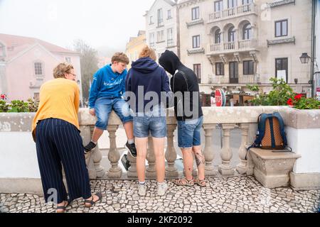 Eine Familie auf dem Stadtplatz von Sintra (Santa Maria e São Miguel, São Martinho e São Pedro de Penaferrim), während sich der Bergnebel in Portugal schließt. Stockfoto