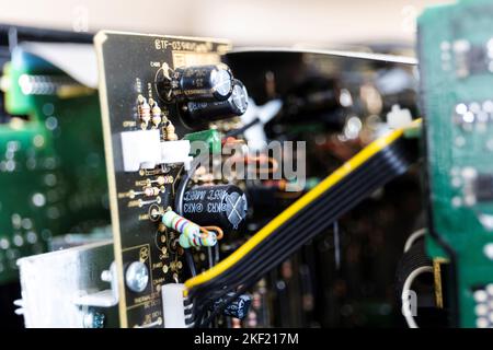 Ein Porträt einer Reihe von elektronischen Komponenten, die in einem offenen Gerät auf eine Leiterplatte oder einen elektronischen Druck gelötet sind. Wir sehen Widerstände und Kondensatoren. Stockfoto