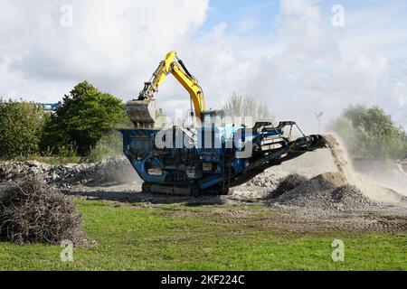 Fahrbare Beton- und Stahlbetonbauschutt-Zerkleinerungsmaschine in Aktion, Bauschutt-Recycling in feinere Fraktionen Stockfoto