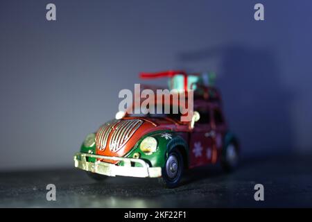 Ein kleines Retro-Weihnachtsauto aus Metall mit Geschenkbox. Konzept für die Zustellung von Geschenken Stockfoto