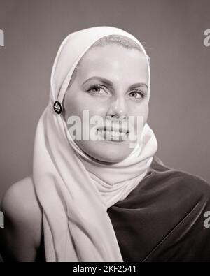 1940S 1950S GLAMOURÖSE BLONDE FRAU PORTRÄT TRÄGT WEISSEN KOPF SCHAL KAPUZE - G381 HAR001 HARS LIFESTYLE FRAUEN STUDIO SHOT GESUNDHEIT HEIM LEBEN KOPIE RAUM DAMEN MAKE-UP PERSONEN STOFF BERUF VERTRAUEN BEDECKUNG AUSDRÜCKE B&W BERUF KOSMETIK MAKE-UP KOPF UND SCHULTERN FRÖHLICHE STILE ANSPRUCHSVOLL KARRIERE BERUFE LÄCHELT KUTTE KONZEPTUELL FRÖHLICH STILVOLL ANGENEHM CHIC MODE GLAMOURÖS JUNGE ERWACHSENE FRAU SCHWARZ UND WEISS KAUKASISCHE ETHNIZITÄT HAR001 KOPFTUCH ALTMODISCH Stockfoto