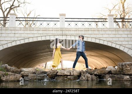 Ein Paar an einer Brücke im Forest Park, flirtet und erkundet zusammen. Stockfoto