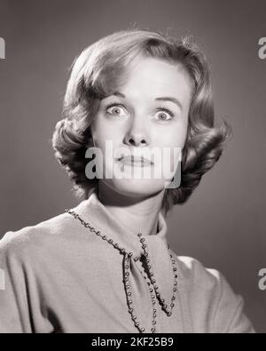 1960S FRAU MIT ERSCHROCKEN SCHOCKIERTEN LUSTIGEN GESICHTSAUSDRUCK MIT WEIT GEÖFFNETEN AUGEN - G5059 DEB001 HARS B&W WIDE EYE CONTACT WONDER BUG-EYED EHRFURCHT HUMORVOLLE KOPF UND SCHULTERN ENTDECKUNG AUFREGUNG VERBLÜFFT KOMISCHEN UNGLAUBEN VERBLÜFFT KONZEPTUELLE VERBLÜFFENDE KOMÖDIE ERSCHRECKT DEB001 AUGENÖFFNER STUN WEITÄUGIGE STAUNENDE REAKTION SPRACHLOS ERSCHRECKTE JUNGE ERWACHSENE FRAU SCHWARZ-WEISS KAUKASISCHEN ETHNIE ALTMODISCH Stockfoto