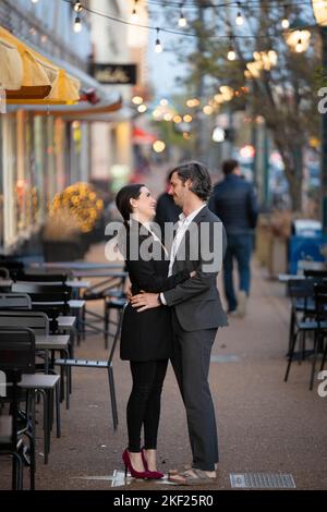 Romantische Fotos eines Paares, das in einer Innenstadt mit Straßenlaternen und Autos im Hintergrund für ein Date unterwegs war. Stockfoto