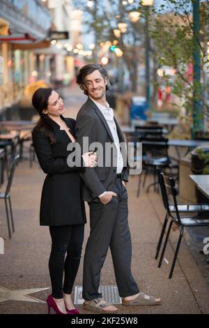 Romantische Fotos eines Paares, das in einer Innenstadt mit Straßenlaternen und Autos im Hintergrund für ein Date unterwegs war. Stockfoto