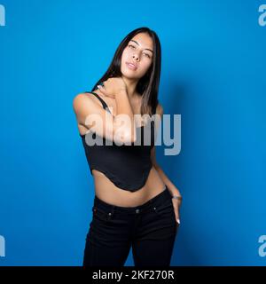 Junge multirassische Teenie Mädchen stehen mit Hand auf Hals blaue Hintergrund und Copy Space Stockfoto