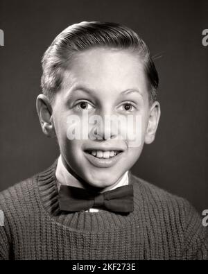 1950S 1960S PORTRAIT NERDY LÄCHELNDER JUNGE MIT FLIEGE UND PULLOVER BEIM BLICK AUF DIE KAMERA - J6504 DEB001 HARS B&W EYE KONTAKT NERD GRAD BOWTIE GLÜCK HELLEN KOPF UND SCHULTERN UND AUFREGUNG NERDY ENTHUSIASTISCHE GELEGENHEIT SCHULE FOTO GRUNDSCHULE BILD STILVOLL DEB001 FLIEGE EIFRIG GRAD SCHULE WACHSTUM JUGENDLICHE PRE-TEEN PRE-TEEN JUNGE SCHWARZ UND WEISS KAUKASISCHEN ETHNIE ALTMODISCH Stockfoto