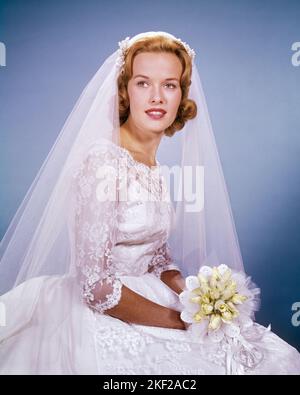 1960S PORTRAIT DER BRAUT TRÄGT HOCHZEITSKLEID SPITZE MIEDER UND ÄRMEL SCHLEIER HÄLT STRAUSS VON WEISSEN ROSEN - KB2572 HAR001 HARS DAMEN EHE PERSONEN PFLEGE SCHLEIER ZEREMONIE BRAUT TRÄUME GLÜCK BRÄUTE BRAUCH UND TRADITION NUPTIAL NUPTIALS ANLASS HOCHZEIT STOLZ MIEDER KONZEPTIONELLE LACY RITUS DER PASSAGE ÄRMEL STILVOLLE MI PERSÖNLICHE BINDUNG ZUNEIGUNG EMOTION HEIRATEN EHE JUNGE ERWACHSENE FRAU KAUKASISCHE ETHNIE HAR001 ALTMODISCH Stockfoto