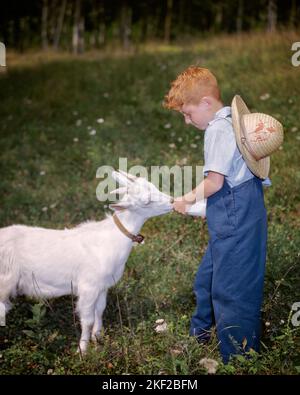 1960S ROTHAARIGE JUNGE FÜTTERUNG JUNGE WEISSE ZIEGE KIND MIT FLASCHE - KG5225 HAR001 HARS KOPIEREN RAUM IN VOLLER LÄNGE TUCH PFLEGE LANDWIRTSCHAFT MÄNNCHEN WINDEL LANDWIRTSCHAFT ZIEGE ABENTEUER CHORE BAUERN ERNÄHRUNG ROTHAARWINDELN BEHAART VERBINDUNG ROTES HAAR VERANTWORTUNG STROH HAT VERBRAUCHEN ZIEGEN HYDRATATION NAHRUNG UNTERSTÜTZEN WACHSTUM JUGENDLICHE ERFRISCHENDE AUFGABE KAUKASISCHE ETHNIZITÄT HAR001 ALTMODISCH Stockfoto