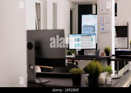 Arbeitsplätze mit Desktop-Geräten auf Holztischen im modernen Coworking-Büro. Leerer Arbeitsplatz, bevor die Mitarbeiter am frühen Morgen zur Arbeit kommen, Arbeitskonzept im Innenbereich. Stockfoto