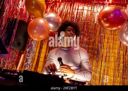afroamerikanischer dj mit Kopfhörern, der Musik spielt und Mikrofon in einem Nachtclub hält Stockfoto