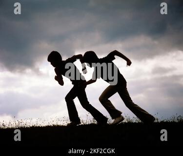 1970S ZWEI SILHOUETTEN ANONYMER JUNGEN BRÜDER, DIE GEGEN DEN BLAUGRAUEN WOLKENHIMMEL ANTRETEN - KJ5267 HAR001 HARS MYSTERY ATHLET ABSTRACT LIFESTYLE SPEED BROTHERS RURAL RUNNERS LEICHTATHLETIK KOPIERE RAUM GEGEN FREUNDSCHAFT GANZLÄNGE KÖRPERLICHE FITNESS INSPIRATION MÄNNER SPORTLICH GESCHWISTER SILHOUETTEN STÜRMISCHE UMRISSE WOLKEN AKTIVITÄT PHYSISCHES ABENTEUER STÄRKE SILHOUETTEN ERHOLUNG KONKURRIERENDE GESCHWISTER STÜRMISCHER HIMMEL KONZEPTIONELLE ATHLETEN ENTKOMMEN FLEXIBILITÄT FREUNDLICHE MUSKELN ANONYMES FUSSRENNEN GRAUES WACHSTUM JUGENDLICHE POSIEREN PRE-TEEN PRE-TEEN JUNGE KAUKASISCHE ETHNIZITÄT BEWÖLKT HAR001 ALTMODISCH Stockfoto