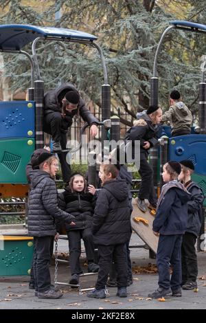 Spielerische orthodoxe jüdische Kinder spielen in der Pause an ihrer Jeschiwa auf einem gleitenden Teich. In brooklyn, New York. Stockfoto