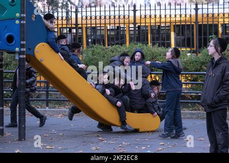 Spielerische orthodoxe jüdische Kinder spielen in der Pause an ihrer Jeschiwa auf einem gleitenden Teich. In brooklyn, New York. Stockfoto